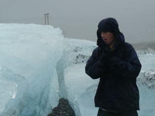man bundled up next to glacier in iceland