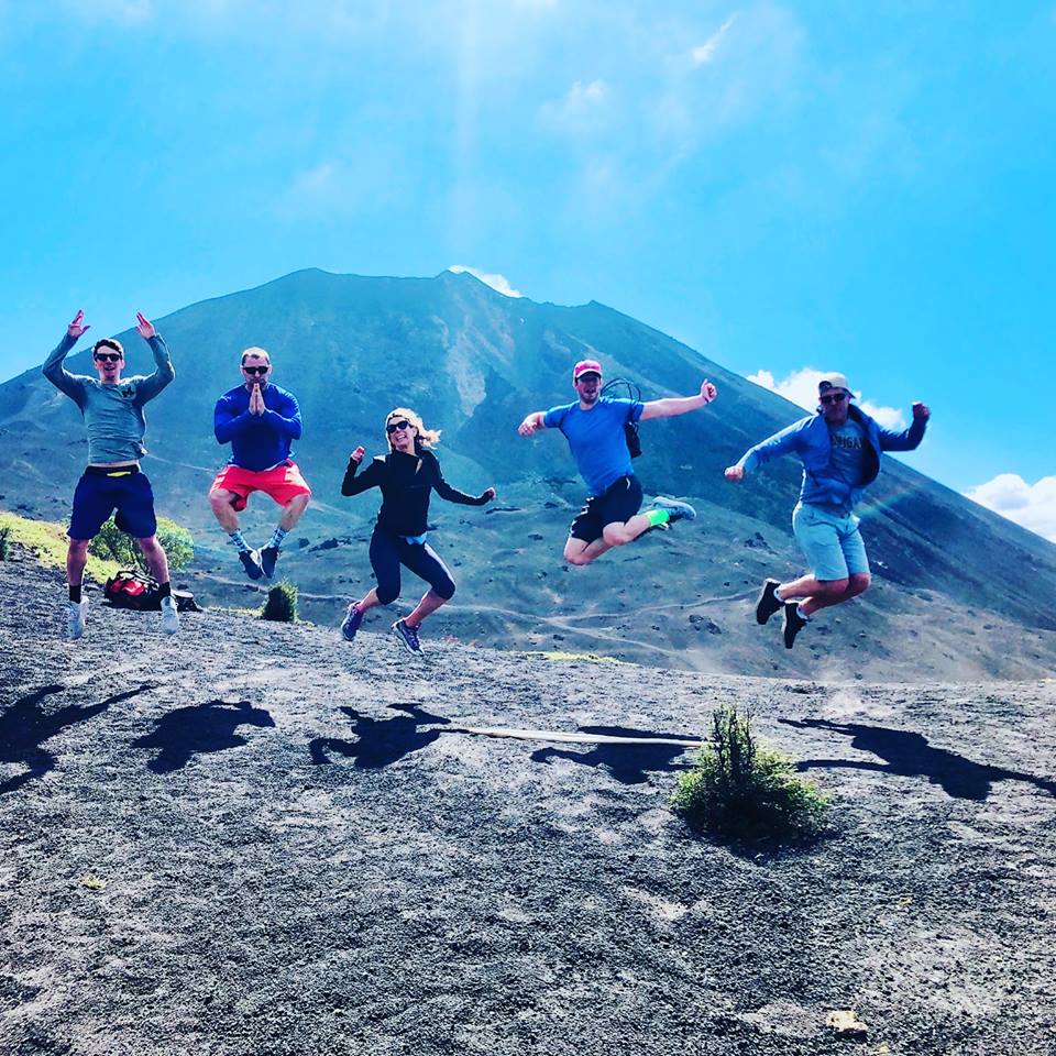 family jumping in front of mountain in guatemala