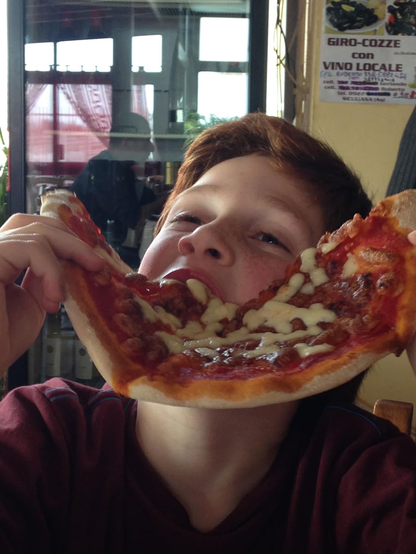 boy eating giant slice of pizza