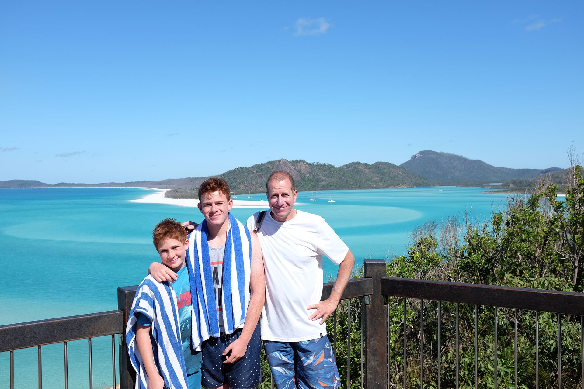 father and sons at whitehaven beach in australia