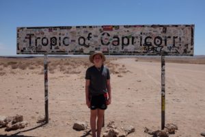 kid standing in front of tropic of capricorn sign